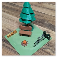 Ein beruhigende Szene, die eine rustikale Holzbank vor einem Baum zeigt.<br />Davor ein kleines Lagerfeuer.<br />Daneben ein Fahrrad in einem Fahrradständer aus einer zweistelligen Zahl (hier: 60).<br /><br />Zur Individualisierung mit Namen (hier: Anne)